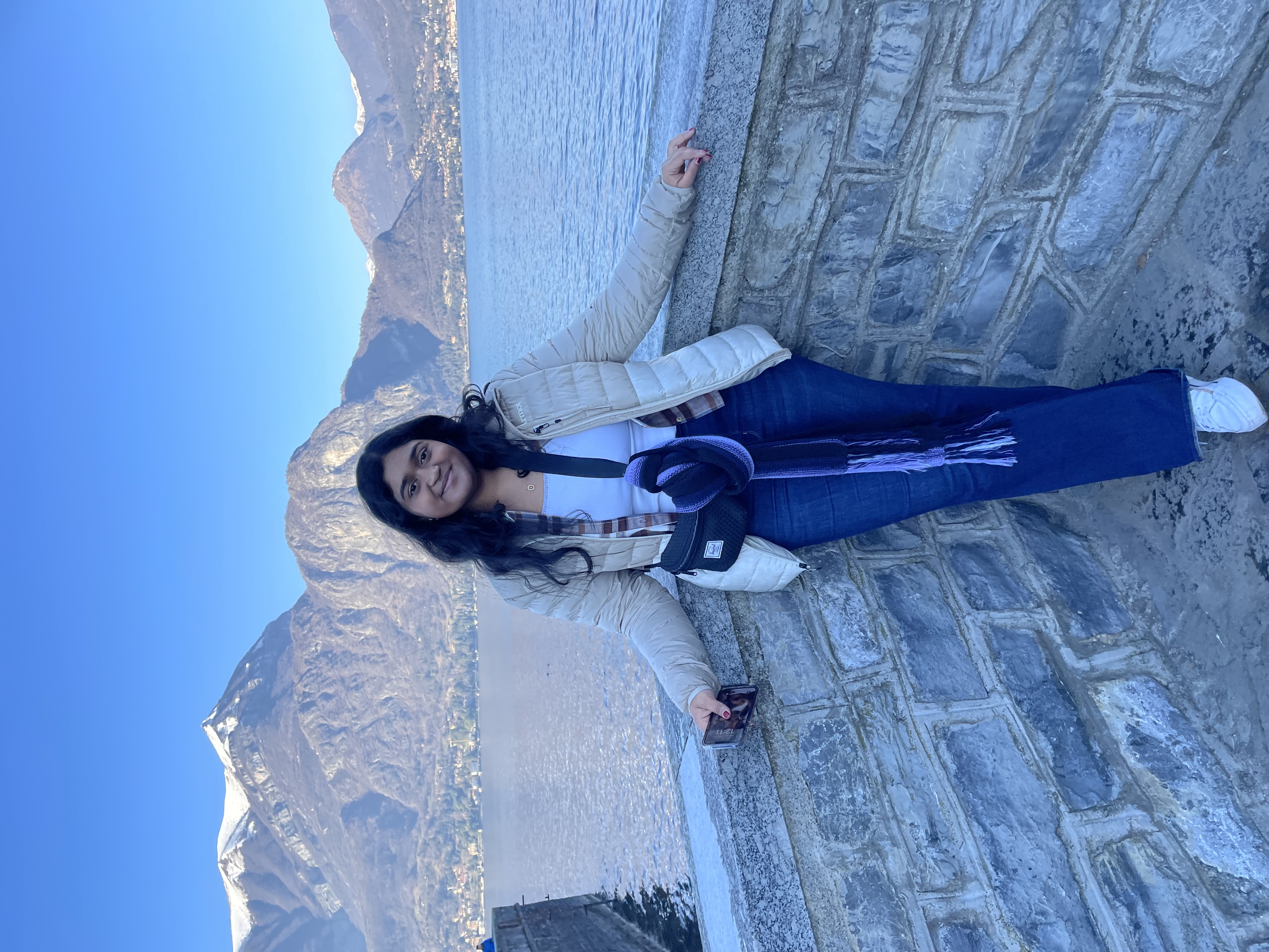 Shreya Motaganahalli Person standing on a paved area with mountains and a clear blue sky in the background.